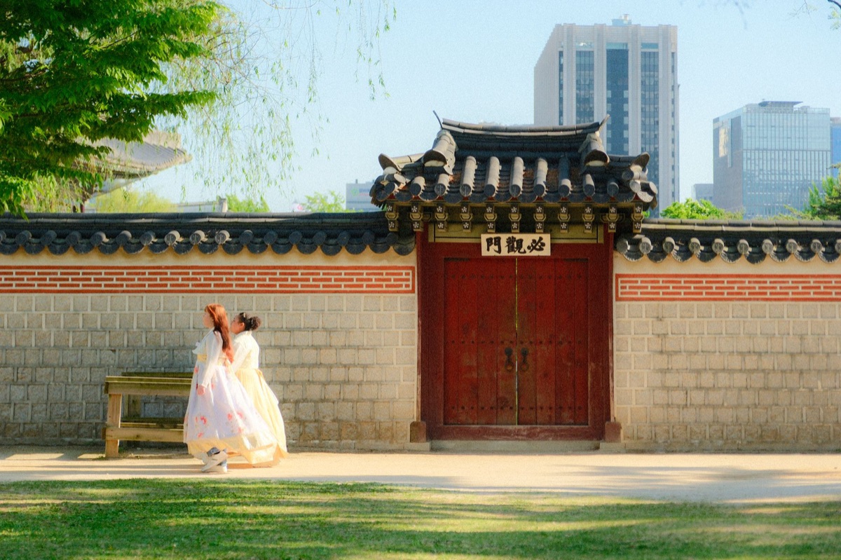 Jongere vrouw in traditionele Koreaanse Hanbok in historische setting.