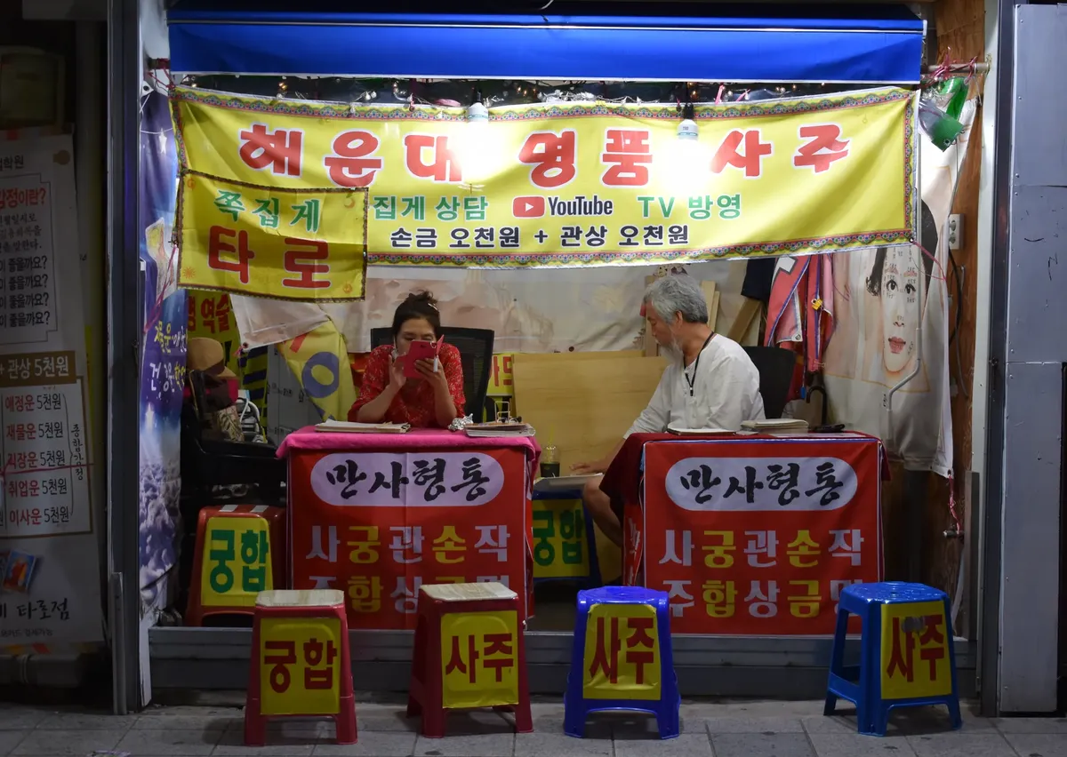 A bustling fortune telling stall in Busan, South Korea, showcasing the local street market culture at night.