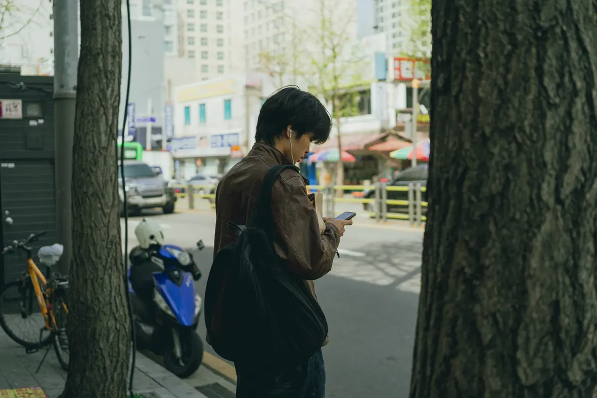 A young man using his smartphone while walking through a busy street in Seoul, South Korea.